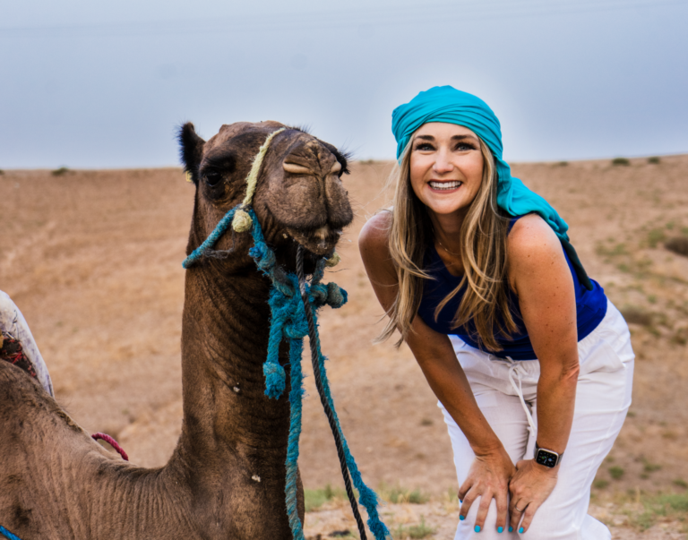 Smiling traveller beside a camel in the Agafay desert, Morocco travel photography by Nomad’s Eye
